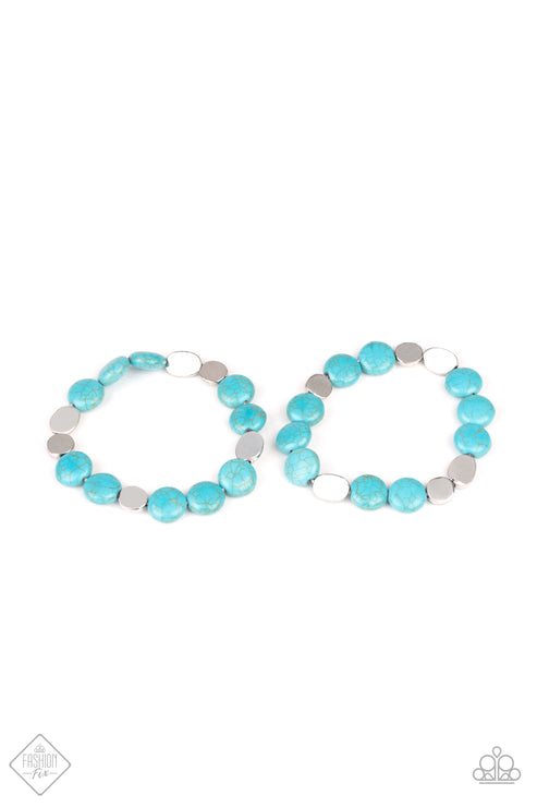 A collection of round turquoise stones and flat silver beads are threaded along stretchy bands that wrap around the wrist to create earthy layers.  Sold as one set of two bracelets.