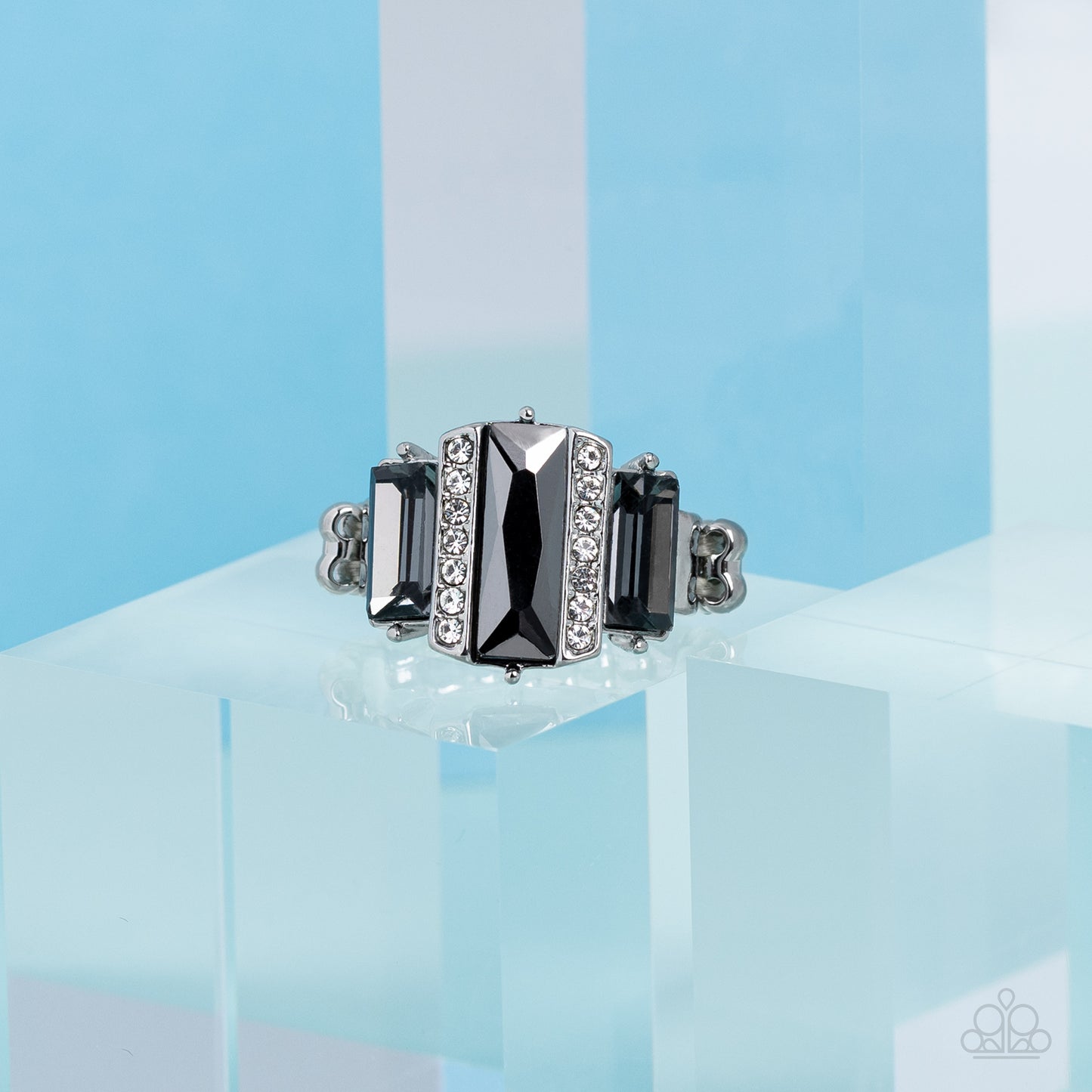 Paparazzi Accessories - A Glitzy Verdict - Silver Ring bordered by two rows of dainty white rhinestones, an emerald cut hematite rhinestone adorns the center of a band dotted with a pair of smoky emerald cut rhinestones, resulting into a jaw-dropping dazzle across the finger. Features a stretchy band for a flexible fit.  Sold as one individual ring.