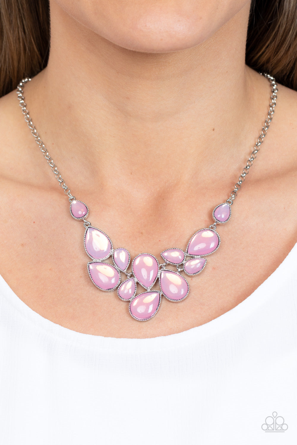 Paparazzi Accessories - Keeps GLOWING and GLOWING - Pink Necklaces a cascade of glassy opalescent pink teardrops are encased in studded silver frames, ultimately clustering below the collar to create an enchanting pop of color. Features an adjustable clasp closure.  Sold as one individual necklace. Includes one pair of matching earrings.