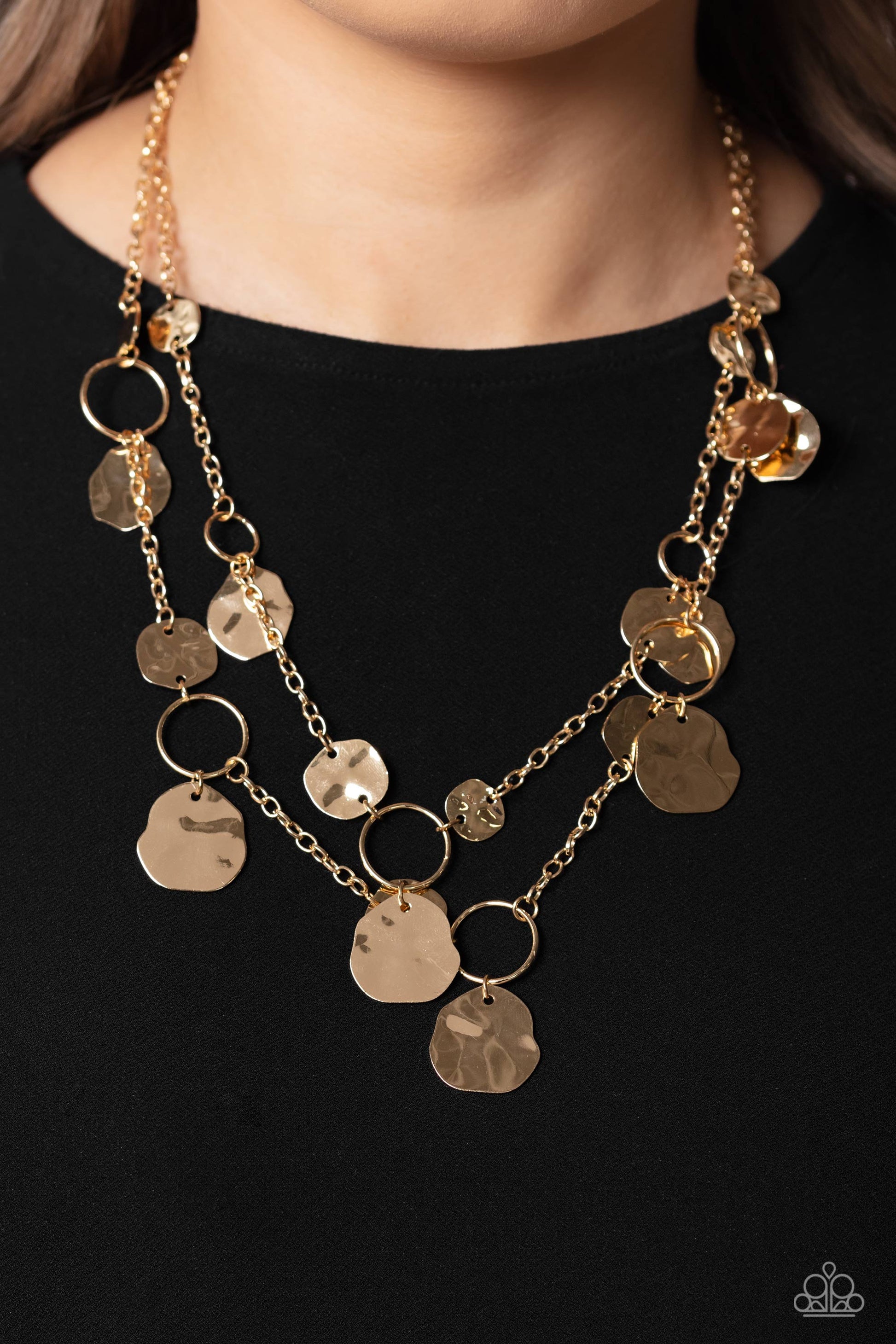 Paparazzi Accessories - Hammered Horizons - Gold Necklaces Infused along a double-stranded gold chain, smooth gold hoops and abstract, hammered gold discs fall down the neckline for an edgy, boisterous display. Features an adjustable clasp closure.  Sold as one individual necklace. Includes one pair of matching.