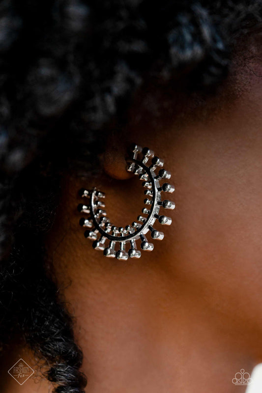 Tactile silver studs fan out along a classic silver hoop, erupting into a brilliant display of texture and sheen. Smaller studs line the inner edge of the hoop, adding additional eye-catching detail to the adventurous design. Earring attaches to a standard post fitting. Hoop measures approximately 1 1/4" in diameter.  Sold as one pair of hoop earrings.
