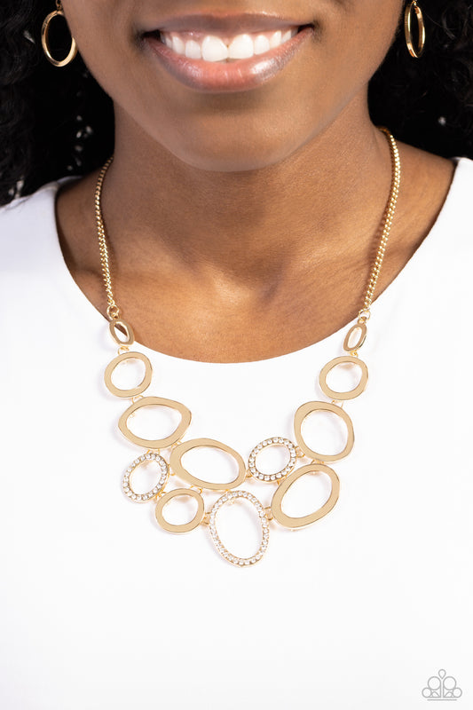 Paparazzi Accessories - Limelight Lead - Gold Necklaces oblong gold rings in varying sizes intermingle with oblong gold rings dusted with a border of white rhinestones for a sparkly monochromatic statement that cascades down the neckline from a classic gold chain. Features an adjustable clasp closure. Sold as one individual necklace. Includes one pair of matching earrings.