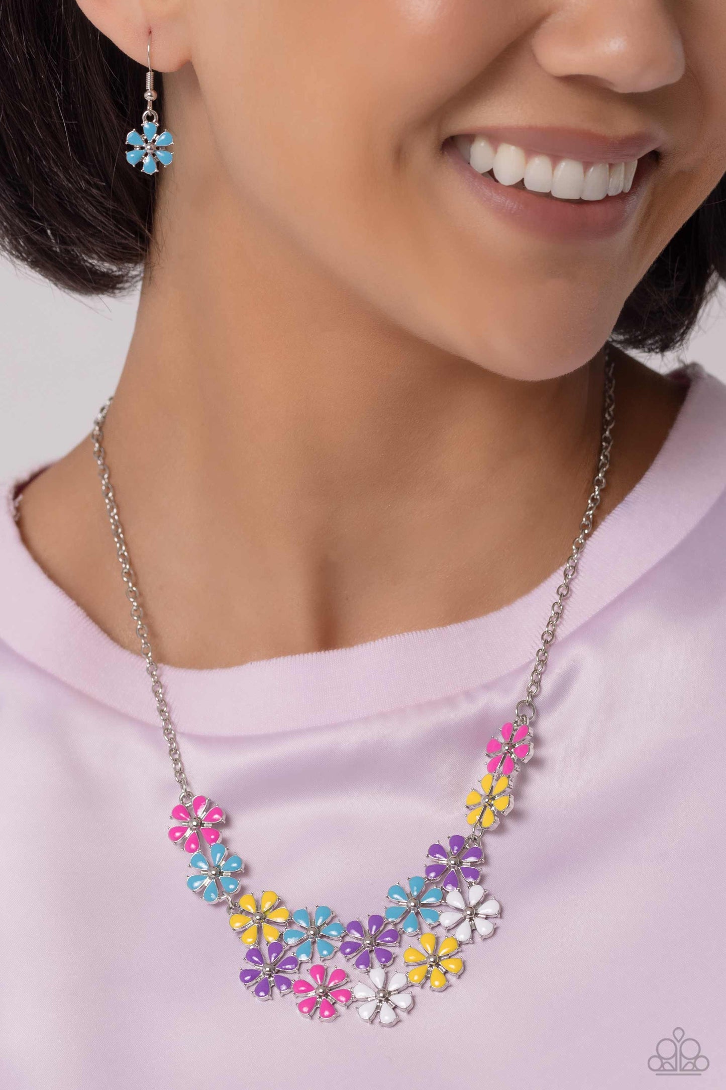 Painted in vivacious shades of hot pink, turquoise, yellow, purple, and white, a collection of silver studded flowers glide across the chest from a dainty silver chain for a whimsical array. Features an adjustable clasp closure. Painted in vivacious shades of hot pink, turquoise, yellow, purple, and white, a collection of silver studded flowers glide across the chest from a dainty silver chain for a whimsical array. Features an adjustable clasp closure.  Featured inside The Preview at Made for More!