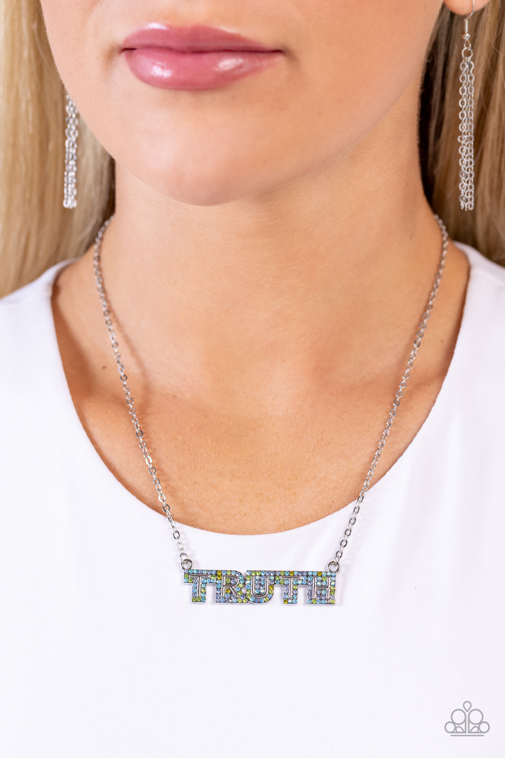 Paparazzi Accessories - Truth Trinket - Blue Necklaces encrusted in glassy olive, Montana, aquamarine, and blue iridescent rhinestones, the silver word "TRUTH" connects to a dainty silver chain, creating an inspirational pendant below the collar. Features an adjustable clasp closure. Due to its prismatic palette, color may vary.  Sold as one individual necklace. Includes one pair of matching earrings.