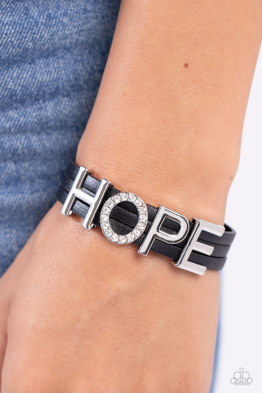 Paparazzi Accessories - Hopeful Haute - Black Bracelets threaded along layers of black leather strands, glistening silver letters form the word "HOPE" with the "O" embossed in white rhinestones for a dazzling statement. Features a magnetic closure.  Sold as one individual bracelet.