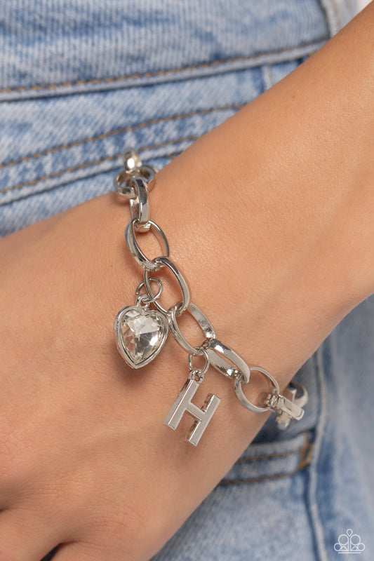 Paparazzi Accessories - Guess Now Its INITIALS - "H" White Bracelets a simple collection of silver charms — including a white rhinestone heart pressed in a silver frame and a sleek letter "H" — dance from a chunky silver chain around the wrist, creating a sentimental fringe. Features an adjustable clasp closure.  Sold as one individual bracelet.