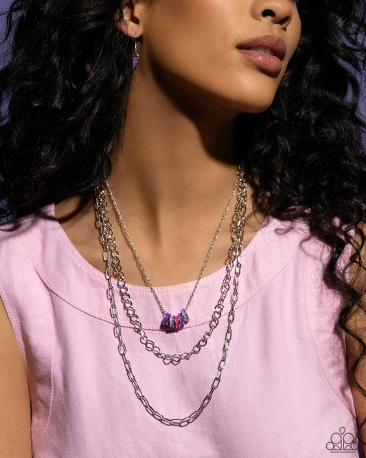 <p>Paparazzi Accessories - Colorful Cadet - Purple Necklaces three mismatched silver chains cascade and layer along the neckline for a sleek look. Strung along the uppermost dainty silver chain, a collection of hot pink, lavender, and purple-painted silver rings add an optimistic splash of color to the look. Features an adjustable clasp closure.</p> <p><i>Sold as one individual necklace. Includes one pair of matching earrings.</i></p>