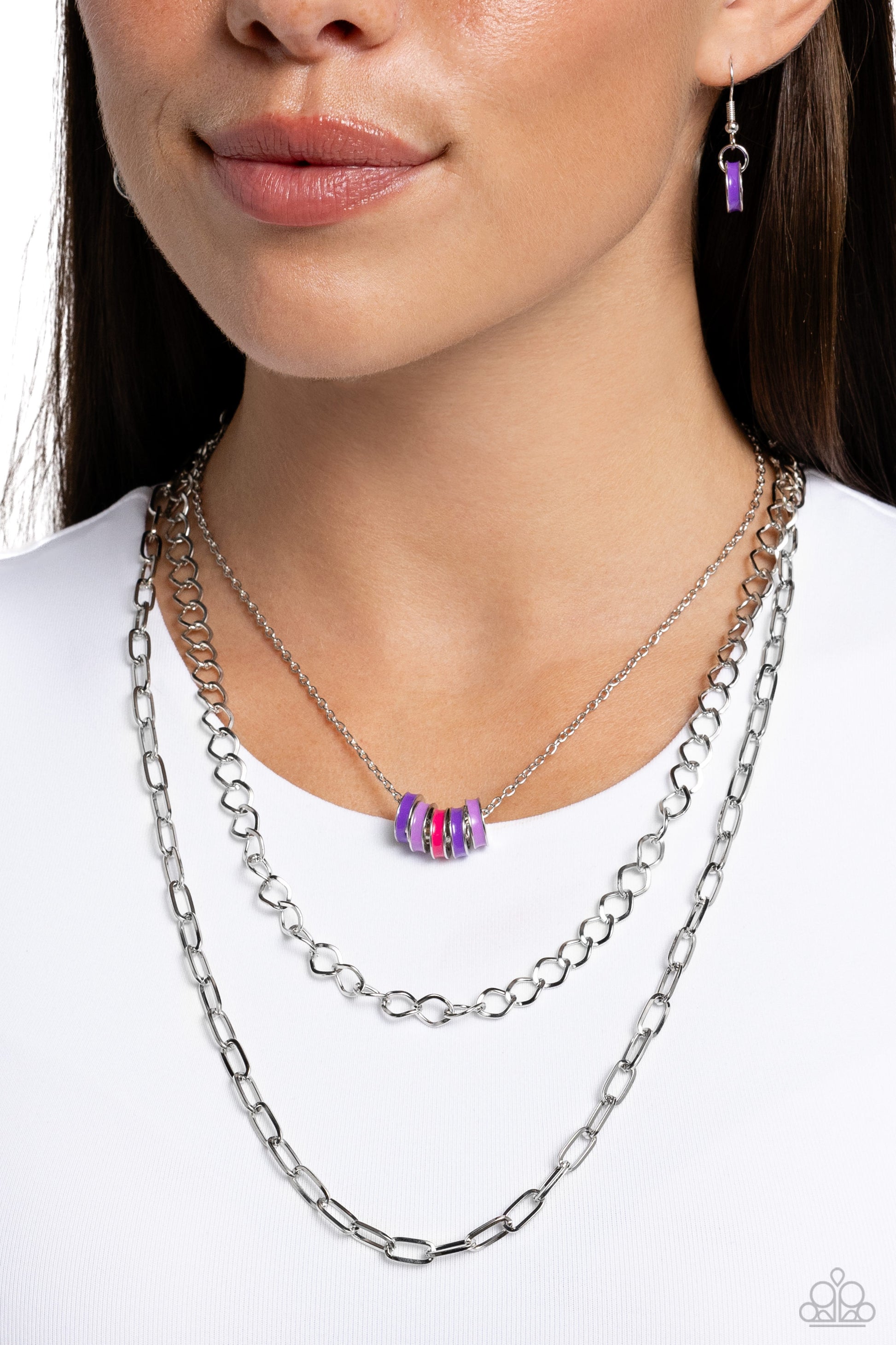 <p>Paparazzi Accessories - Colorful Cadet - Purple Necklaces three mismatched silver chains cascade and layer along the neckline for a sleek look. Strung along the uppermost dainty silver chain, a collection of hot pink, lavender, and purple-painted silver rings add an optimistic splash of color to the look. Features an adjustable clasp closure.</p> <p><i>Sold as one individual necklace. Includes one pair of matching earrings.</i></p>