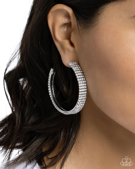Paparazzi Accessories - Stacked Symmetry - White Hoop Earrings set in silver square fittings, row after row of white rhinestones are embellished around a silver hoop for a dazzling design. Earring attaches to a standard post fitting. Hoop measures approximately 2" in diameter. Sold as one pair of hoop earrings.
