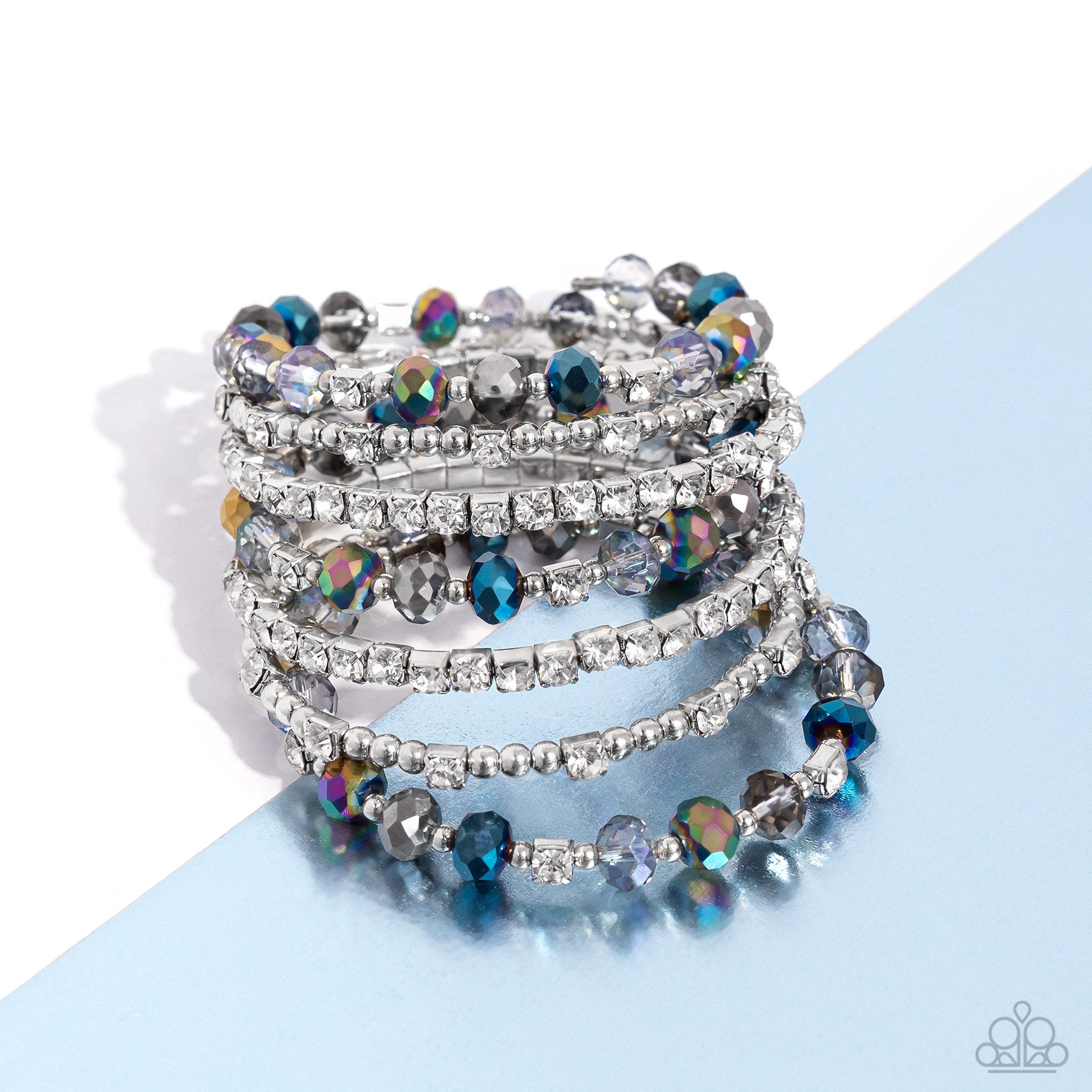 <p>Paparazzi Accessories - Sizzling Stack - Multi Bracelets threaded along a coiled wire, silver beads, white rhinestones in silver square fittings, and oil spill, blue, silver, and transparent faceted beads curl around the wrist, creating an eye-catching, infinity wrap-style bracelet around the wrist.</p> <p><i>Sold as one individual bracelet.</i></p>