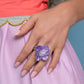 Featuring a warped shell-like texture, an oversized lavender flower glimmers atop the finger for a whimsical finish. Dainty silver studs and clear crystal beads coalesce the center of the flower, adding additional tactile detail. Features a stretchy band for a flexible fit.  Sold as one individual ring.