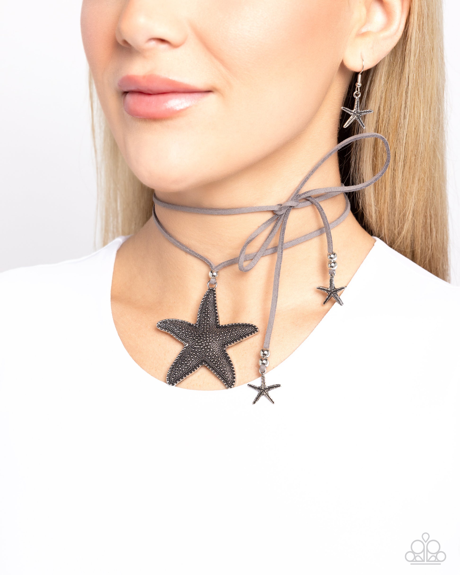Paparazzi Accessories - Starfish Sentiment - Silver Necklaces infused with silver beaded and studded oversized starfish accents, a lengthened strip of gray suede double wraps around the neck, creating a layered choker necklace. Two whimsical silver starfish charms swing from the ends as a silver bead slides up and down the suede strands, adjusting the length of the coastal piece.  Sold as one individual necklace. Includes one pair of matching earrings.