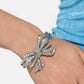 Paparazzi Accessories - It's All A-Bow-t Me - White Bracelets&nbsp;Infused along elastic stretchy bands, airy silver frames gleam along the wrist for a monochromatic display. Encrusted in white rhinestones, an oversized, airy silver bow glitters at the center of the design for a touch of class and refinement.  Sold as one individual bracelet.