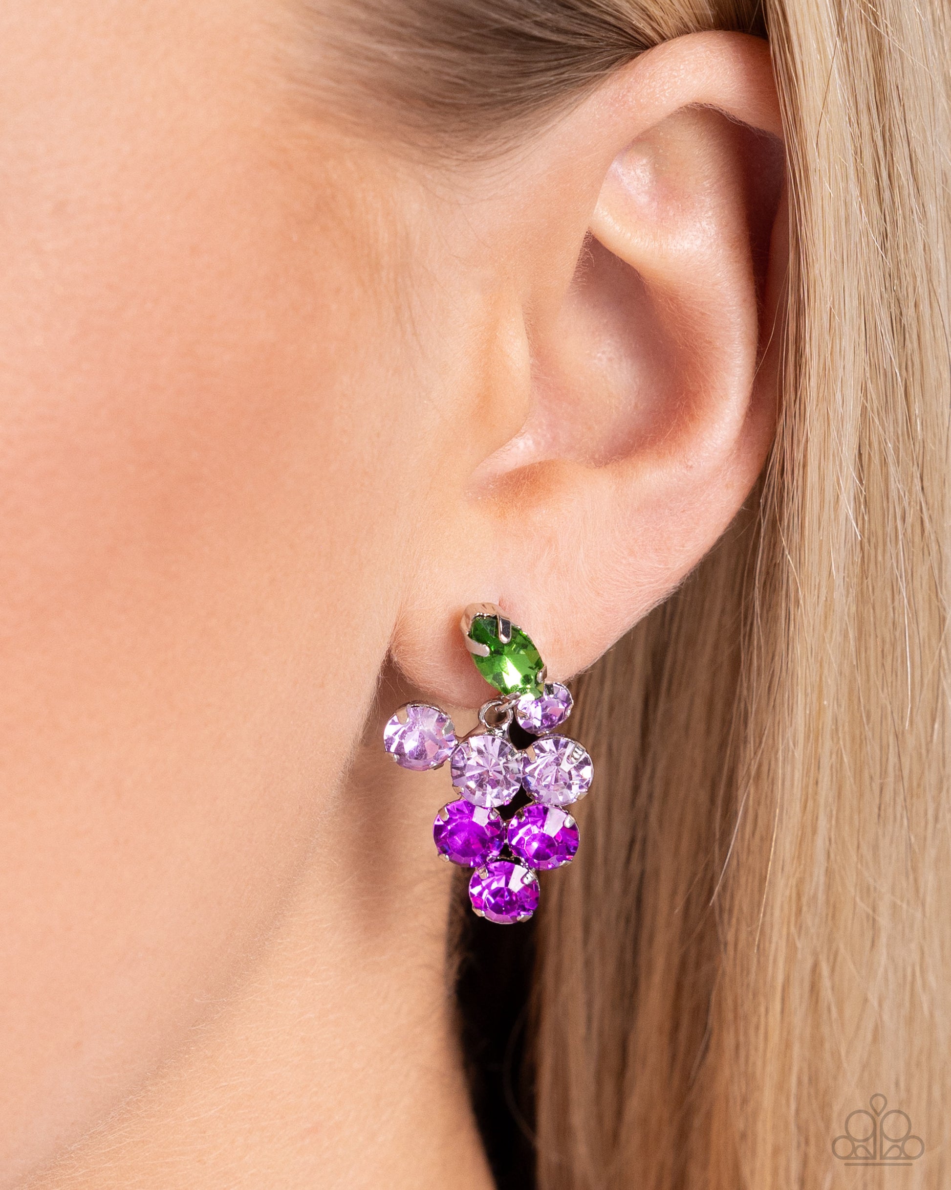 Pronged in silver fittings, a collection of round light purple rhinestones fade to darker purple rhinestones with a solitaire green marquise-cut leaf for an ombré, glittery grape-inspired display. Earring attaches to a standard post fitting.  Sold as one pair of post earrings.