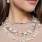 collection of clear, pearl, and textured white and ivory beads combine with silver paperclip chain links, silver beads, ivory beads in various opacities, and brown-swirl patterned reflective beads along the neckline in layers for an everyday elegant look. Features an adjustable clasp closure.  Sold as one individual necklace. Includes one pair of matching earrings.