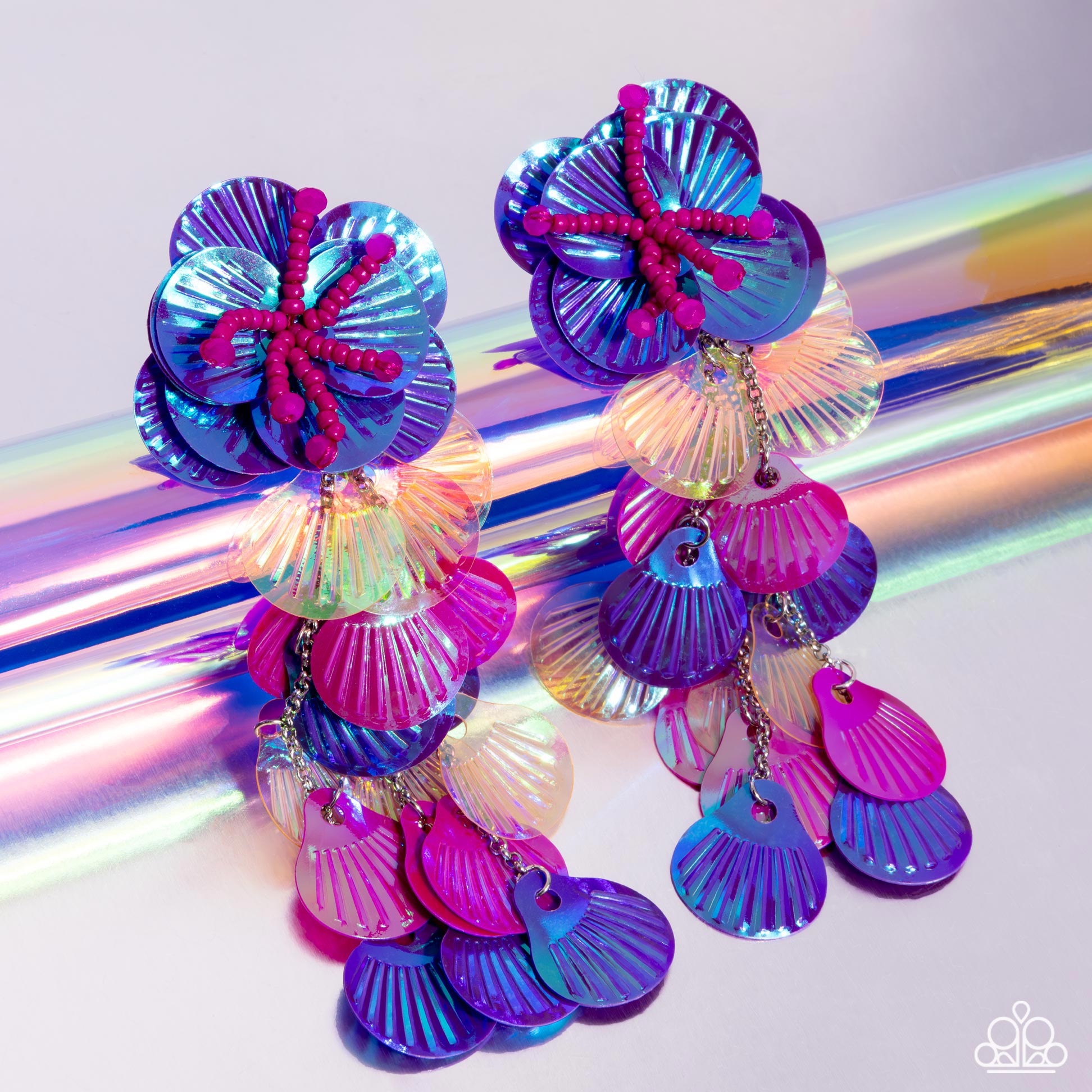 Featuring an iridescent hue, a collection of purple, pink, and orange sequins cascade from a collection of purple sequins that flourish from a hot pink seed beaded starfish for a coastal, chic look. Earring attaches to a standard post fitting. Due to its prismatic palette, color may vary.  Sold as one pair of post earrings.