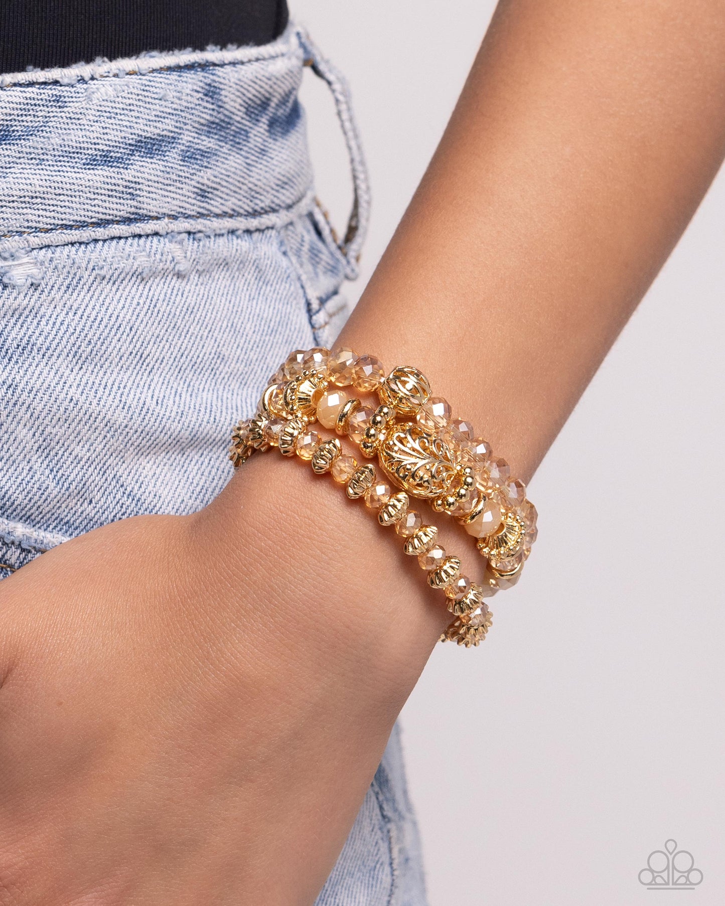 Faceted gold clear and opaque beads, various gold beads, and a vintage-embellished oversized bead stack up the wrist on elastic stretchy bands for a classically colorful look.  Sold as one set of three bracelets.