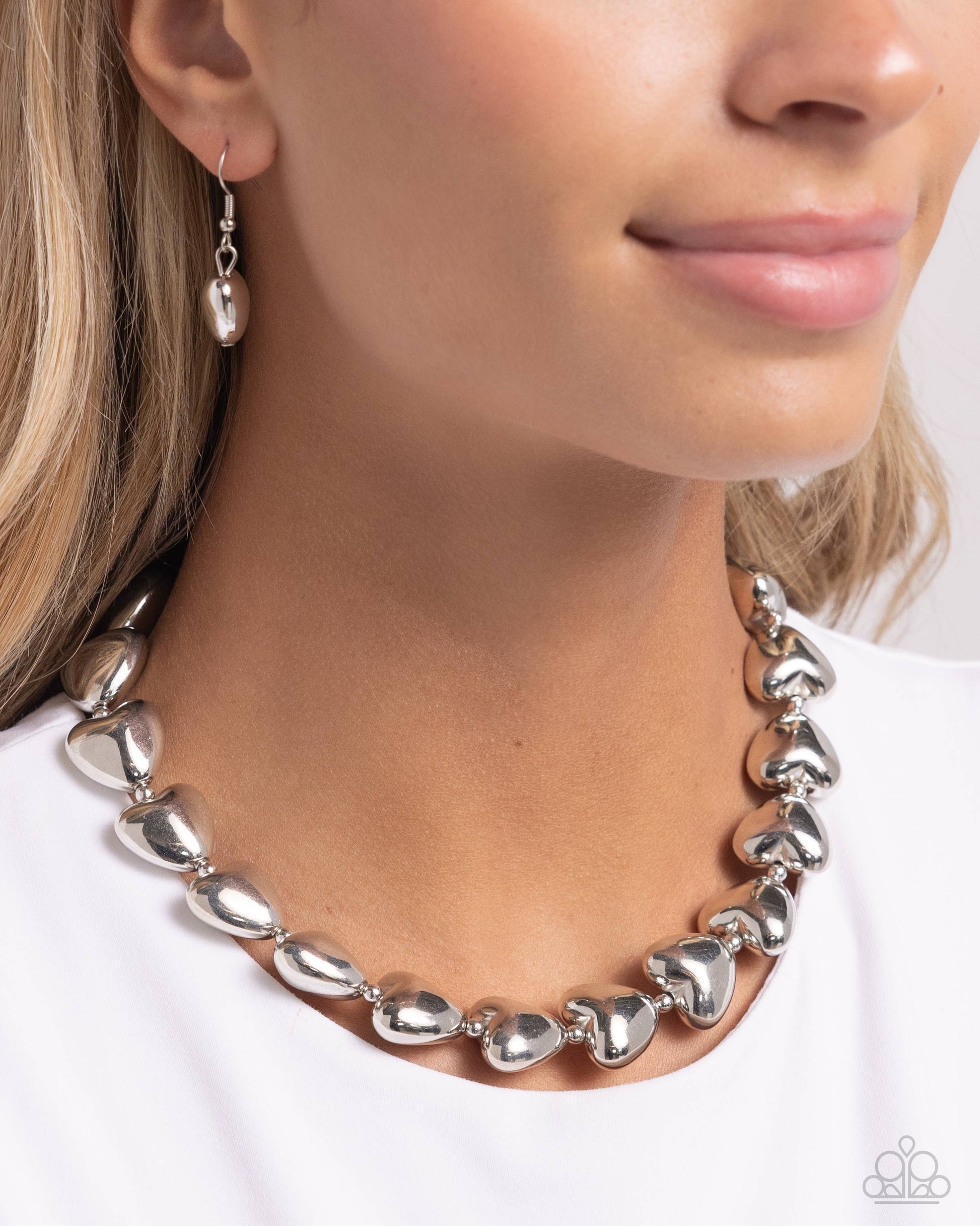 Infused along a classic silver chain, sleek silver hearts alternate with dainty silver beads along the neckline for a romantically refined statement. Features an adjustable clasp closure.  Sold as one individual necklace. Includes one pair of matching earrings.