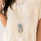 A fringe of antiqued silver feathers and shimmery silver chains dangles from the bottom of a stacked silver frame fanning with striking texture.&nbsp; A smooth turquoise stone dots the tribal inspired pendant for an earthy finish.&nbsp; Features an adjustable clasp closure.  Sold as one individual necklace. Includes one pair of matching earrings.