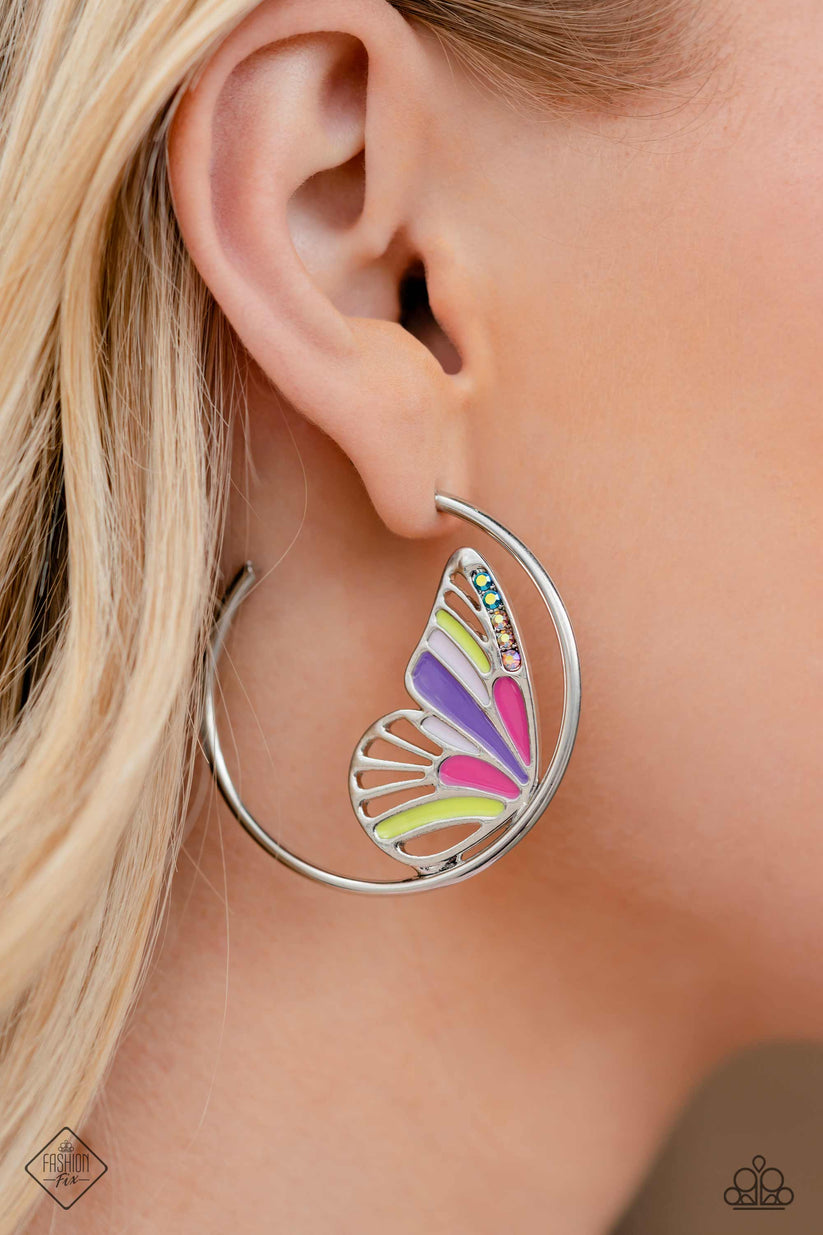 An oversized silver butterfly wing, splashed with baby pink, Fuchsia Fedora, Love Bird, and multicolored iridescent rhinestones, nestles along the inner curve of a glistening silver hoop, creating a whimsically colorful sight. Earring attaches to a standard post fitting. Hoop measures approximately 1 3/4" in diameter. Due to its prismatic palette, color may vary.  Sold as one pair of hoop earrings.