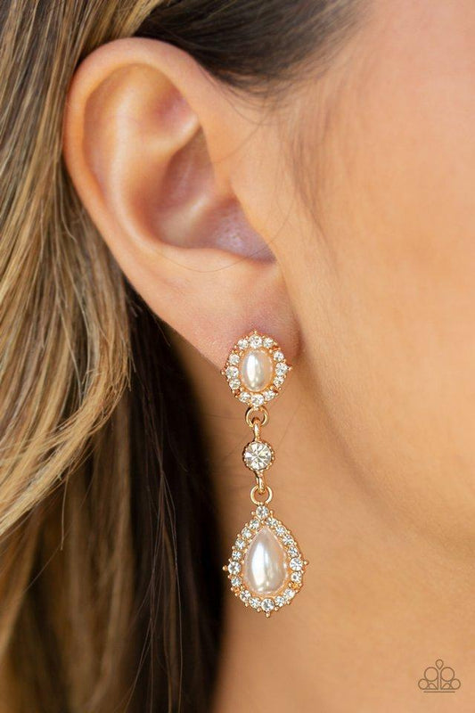 Paparazzi Accessories All- Glowing - Gold Post Earrings a solitaire white rhinestone is linked between two pearly and white rhinestone encrusted frames, creating an elegant lure. Earring attaches to a standard post fitting. Sold as one pair of post earrings.   Perfect for those with sensitive skin.