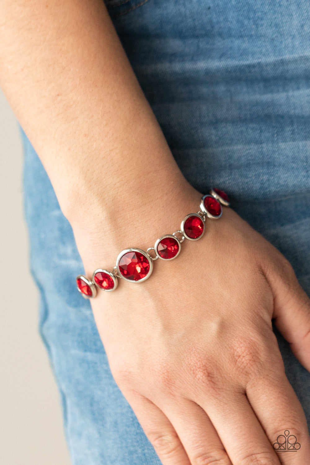 Lustrous Luminosity - Red Rhinestone Bracelets featuring sleek silver fittings, an oversized collection of fiery red gems delicately link around the wrist. The centermost gem is slightly larger than the rest, adding a glamorous finish. Features an adjustable clasp closure.  Sold as one individual bracelet.  Paparazzi Jewelry is lead and nickel free so it's perfect for sensitive skin too!