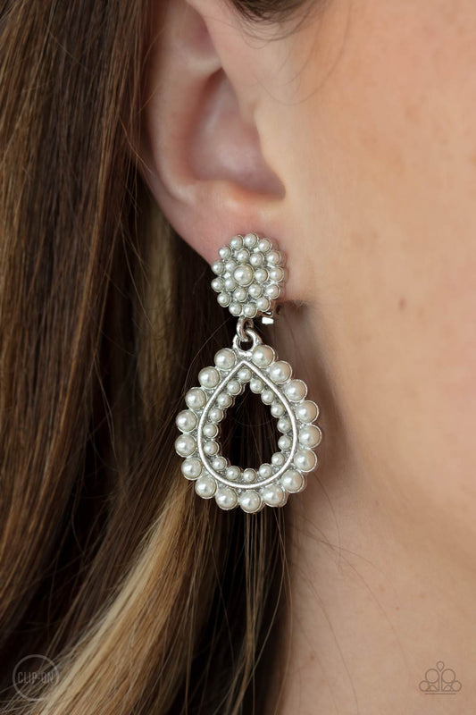 Discerning Droplets - White Clip-On Earrings droplets of pearls dot the surface of a silver teardrop frame that suspends from a round pearl encrusted disc for a classic finish. Earring attaches to a standard clip-on fitting.  Sold as one pair of clip-on earrings.  Paparazzi Jewelry is lead and nickel free so it's perfect for sensitive skin too!