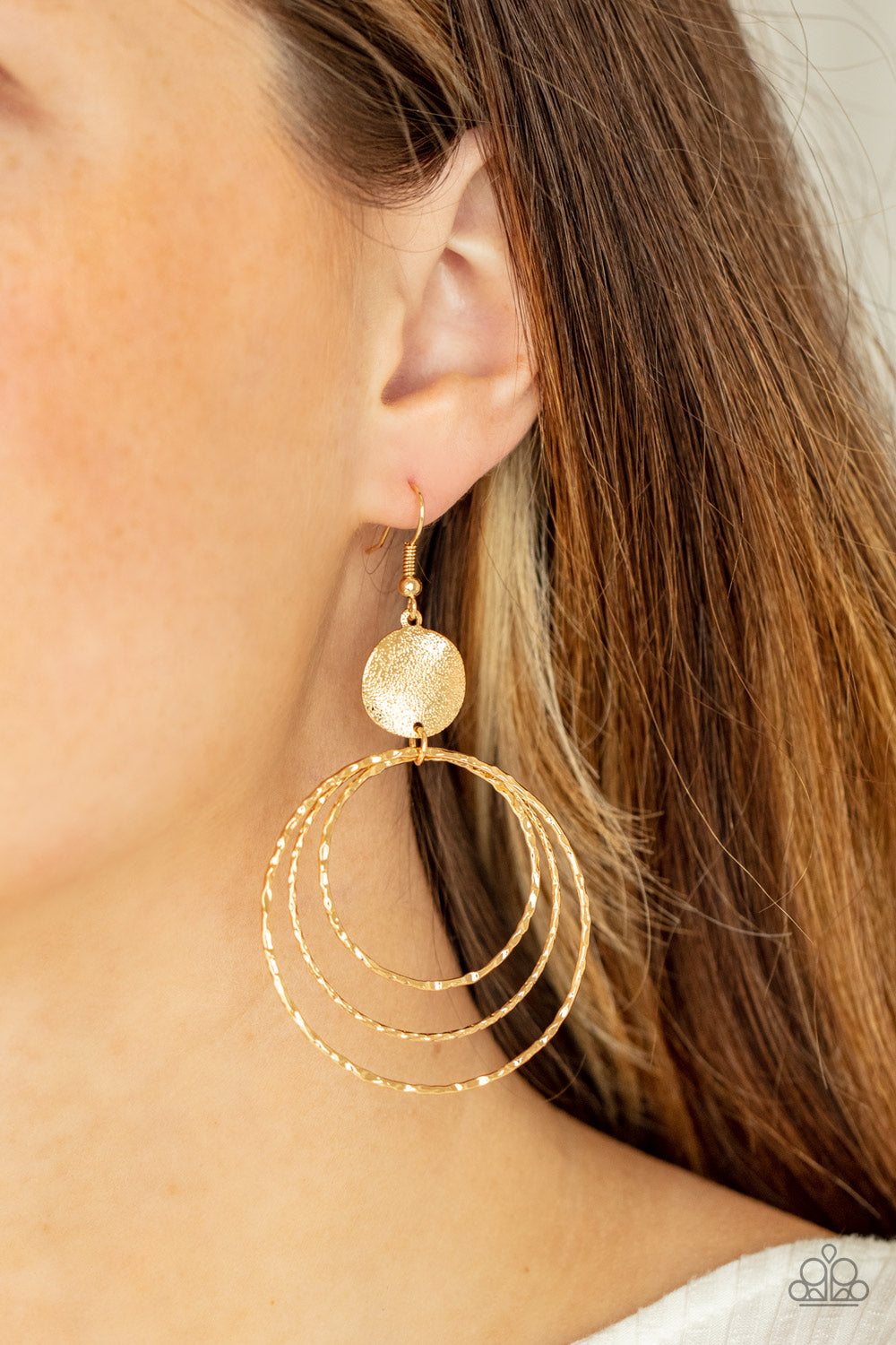 Paparazzi Accessories Universal Rehearsal - Gold Earrings a shimmery wavy gold disc links atop a collection of three delicately hammered gold rings in concentric sizes for an out-of-this-world finish. Earring attaches to a standard fishhook fitting.  Sold as one pair of earrings.  Paparazzi Jewelry is lead and nickel free so it's perfect for sensitive skin too!