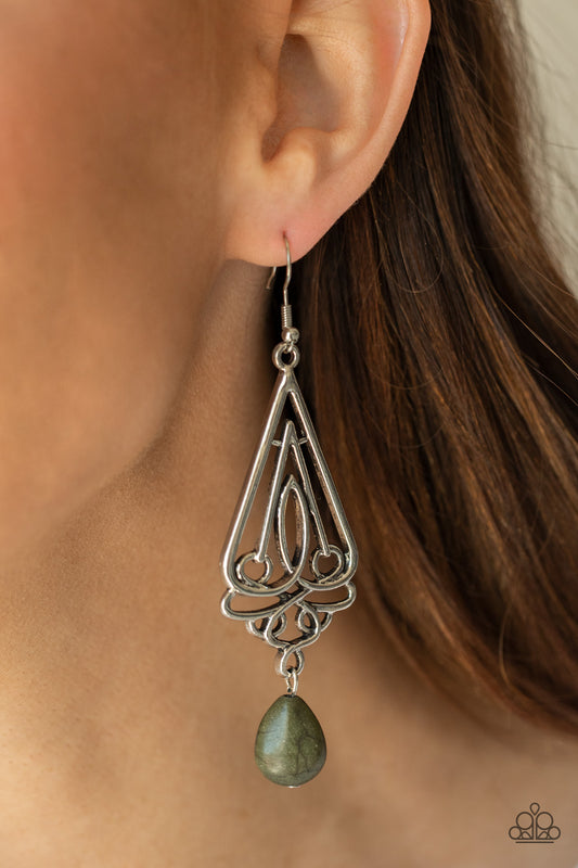 Transcendent Trendsetter - Green Teardrop Stone Earrings - Paparazzi an earthy green teardrop stone swings from the bottom of an ornate triangular frame, creating a seasonal statement. Earring attaches to a standard fishhook fitting.  Sold as one pair of earrings.  Paparazzi Jewelry is lead and nickel free so it's perfect for sensitive skin too!