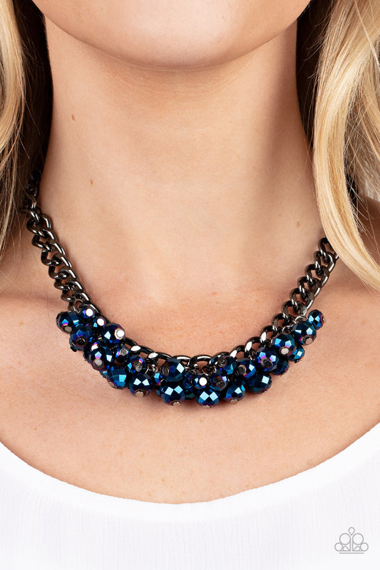 Galactic Knockout - Blue Beaded Necklaces faceted collection of metallic flecked blue beads cluster along the center of a chunky gunmetal curb chain, creating a stellar fringe below the collar. Features an adjustable clasp closure.  Sold as one individual necklace. Includes one pair of matching earrings.