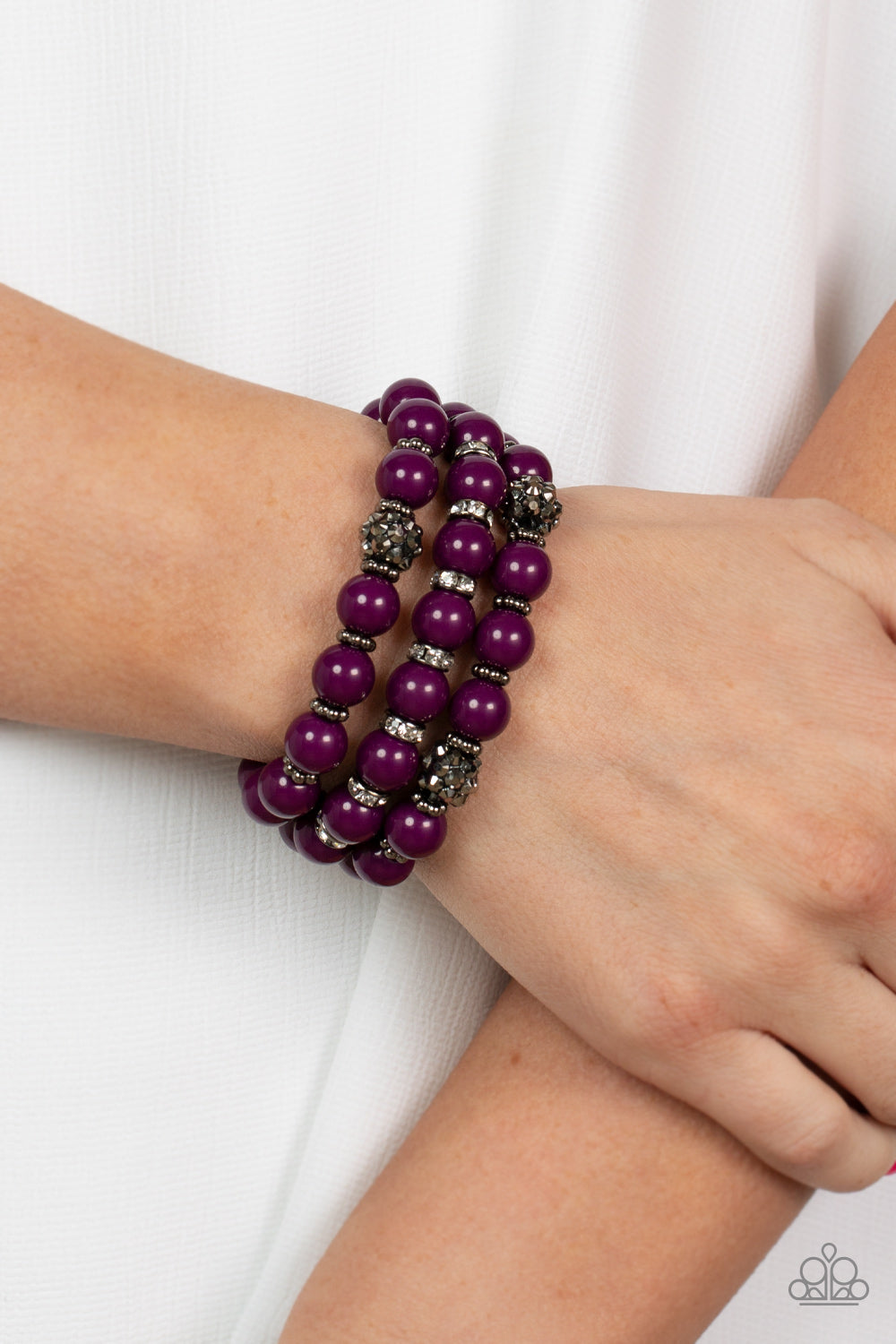 Paparazzi Accessories Poshly Packing - Purple Stretchy Bracelets a posh collection of polished purple beads, studded gunmetal rings, white rhinestone encrusted rings, and hematite dotted beads are threaded along stretchy bands around the wrist, creating sassy layers.  Featured inside The Preview at GLOW!  Sold as one set of three bracelets.