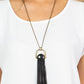 Winslow Wanderer - Brass and Leather Necklaces strips of black leather fan out from the bottom of a round black stone that is threaded along a metal rod that attaches to the bottom of a brass horseshoe frame. The earthy pendant swings from the bottom of an extended brass chain, resulting in a wildly wonderful tassel. Features an adjustable clasp closure.  Sold as one individual necklace. Includes one pair of matching earrings.