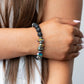Volcanic Vacay - Multi Lava Bead Bracelets  an earthy collection of black lava rock beads, dainty silver discs, and oil spill metallic pebbles are threaded along a stretchy band around the wrist, resulting in an edgy look.  Sold as one individual bracelet.