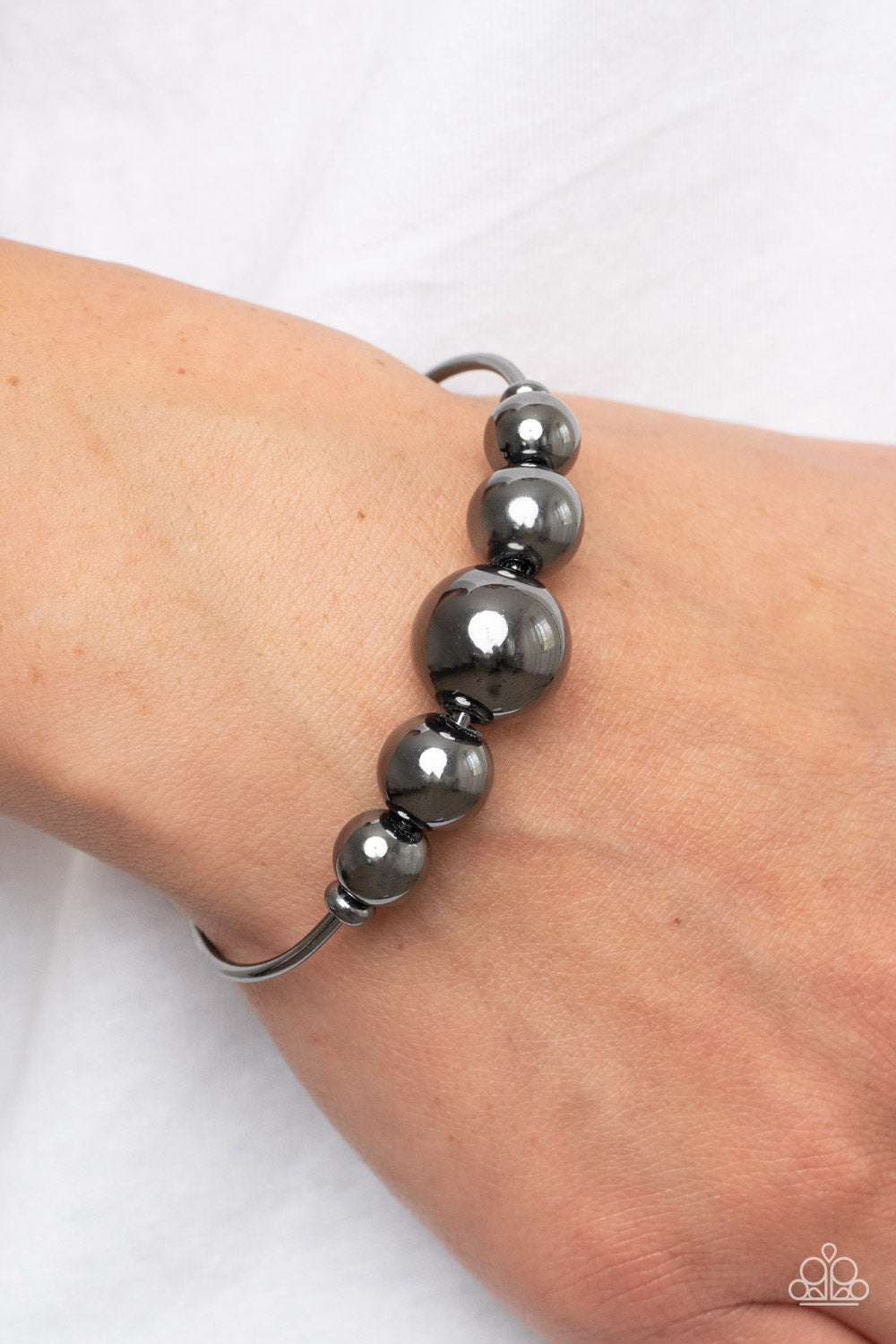 Gradually increasing in size, an oversized collection of gunmetal beads are threaded along a dainty gunmetal cuff for a dramatic industrial display.  Sold as one individual bracelet.