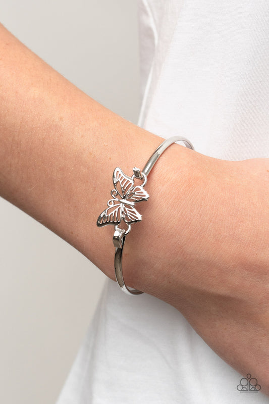 Did I Flutter? - Silver Butterfly Bangle Bracelets attached to a shiny silver bangle-like bracelet, a silver butterfly flutters atop the wrist for a dainty fashion. Features a hook and eye closure.  Sold as one individual bracelet.