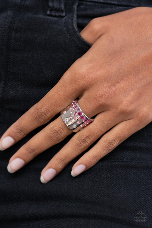 Paparazzi Accessories Sizzling Sultry - Pink Rhinestone Rings featuring iridescent and glassy finishes, glitzy rows of pink and multicolored rhinestones are haphazardly sprinkled across the front of a thick silver band for a colorful splash of ombre sparkle. Features a stretchy band for a flexible fit.  Sold as one individual ring.