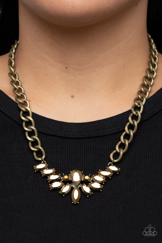 Come At Me - Brass Arum Rhinestone Necklaces glitzy marquise cut aurum rhinestones fan out from the bottom of an oversized teardrop aurum rhinestone, resulting in a gritty pendant at the bottom of a chunky brass chain for a sassy statement. Features an adjustable clasp closure.  Sold as one individual necklace. Includes one pair of matching earrings.
