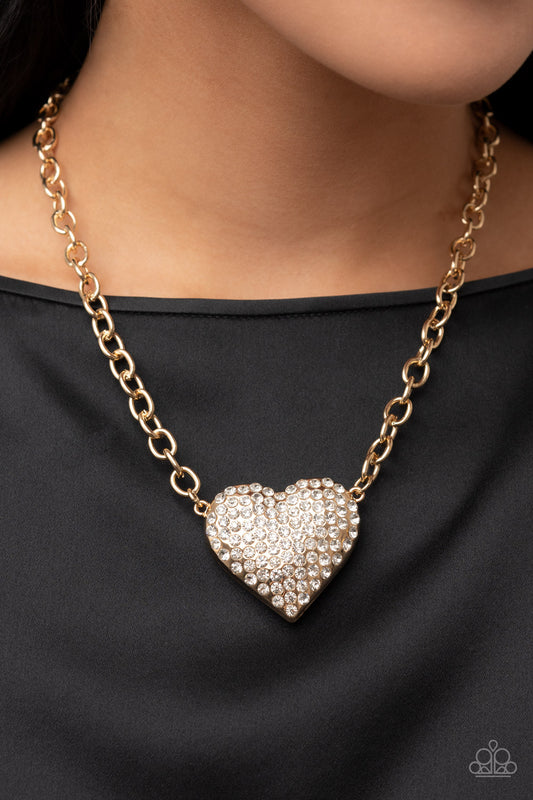 Heartbreakingly Blingy - Gold Rhinestone Heart Necklaces a dramatically oversized gold heart frame is encrusted in row after row of dazzling white rhinestones, resulting in a heart-racing sparkle below the collar. Features an adjustable clasp closure.  Sold as one individual necklace. Includes one pair of matching earrings.
