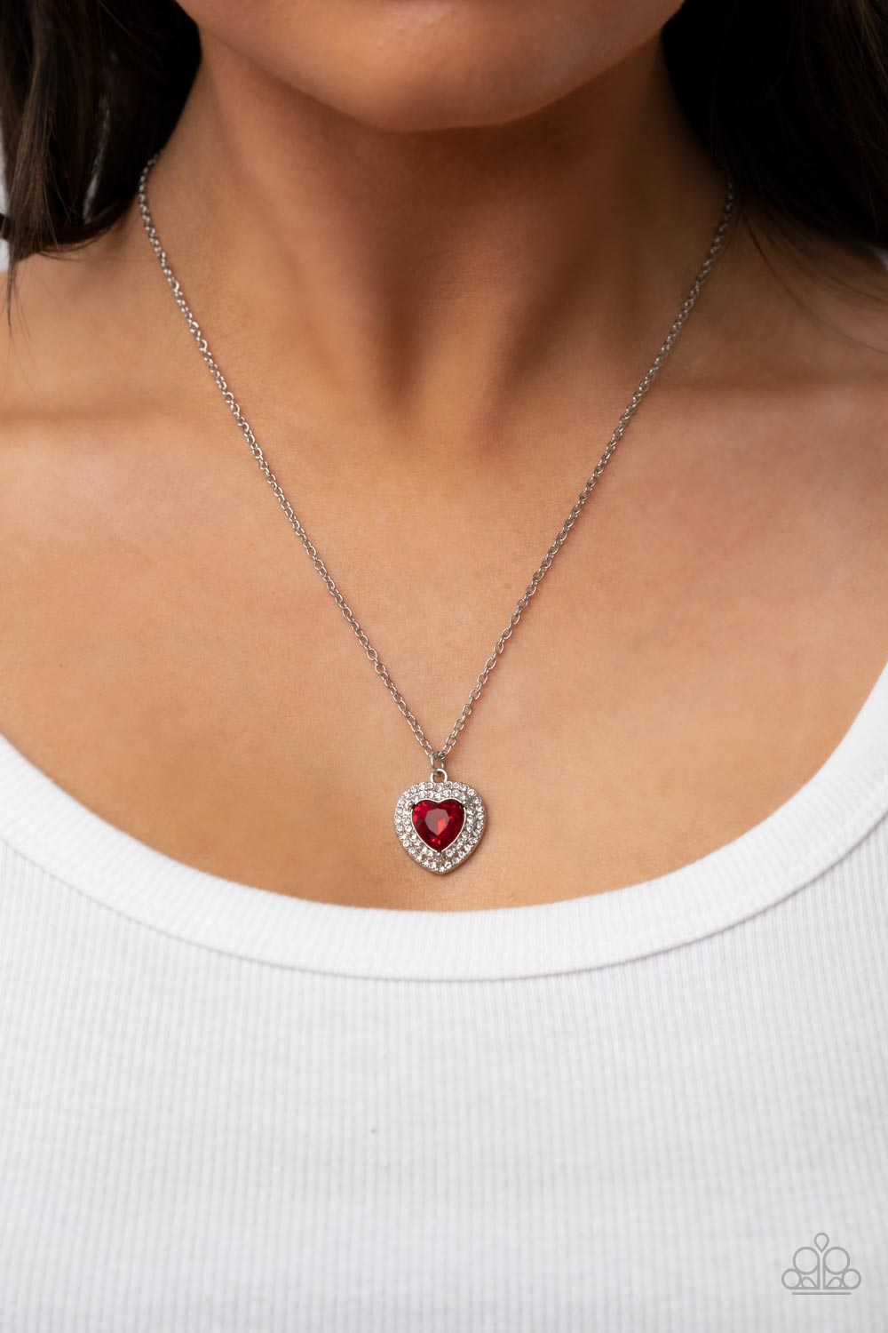 Taken With Twinkle - Red Heart Rhinestone Necklaces bordered in stacked rows of glassy white rhinestones, a fiery red heart shaped gem sparkles at the center of a dainty silver chain for a flirtatious fashion. Features an adjustable clasp closure.  Sold as one individual necklace. Includes one pair of matching earrings.