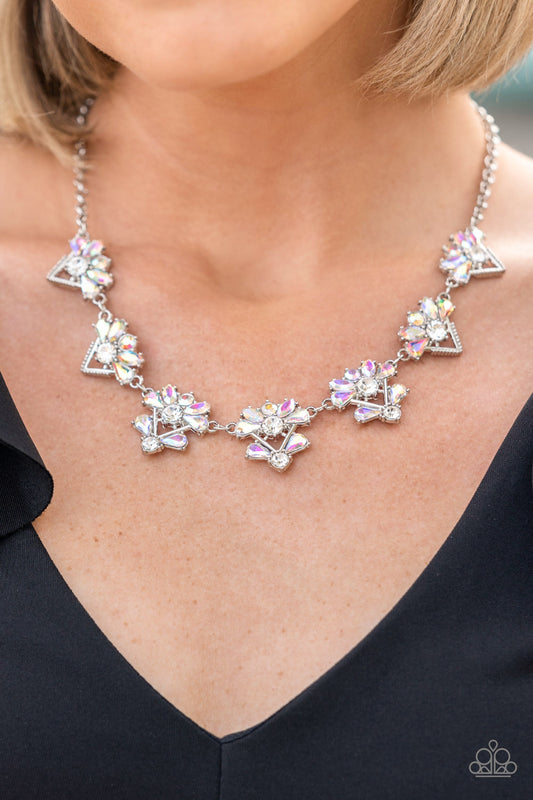 Extragalactic Extravagance - Multi Rhinestone EMP Necklaces featuring a stellar radiance, clusters of teardrop and marquise cut iridescent rhinestones fan out from white rhinestone centers along the tops of studded and pronged triangular frames. The centermost frames feature embellished bottoms, adding an extra splash of cosmic iridescence as the celestial frames link into an out-of-this-world sparkle below the collar. Features an adjustable clasp closure.