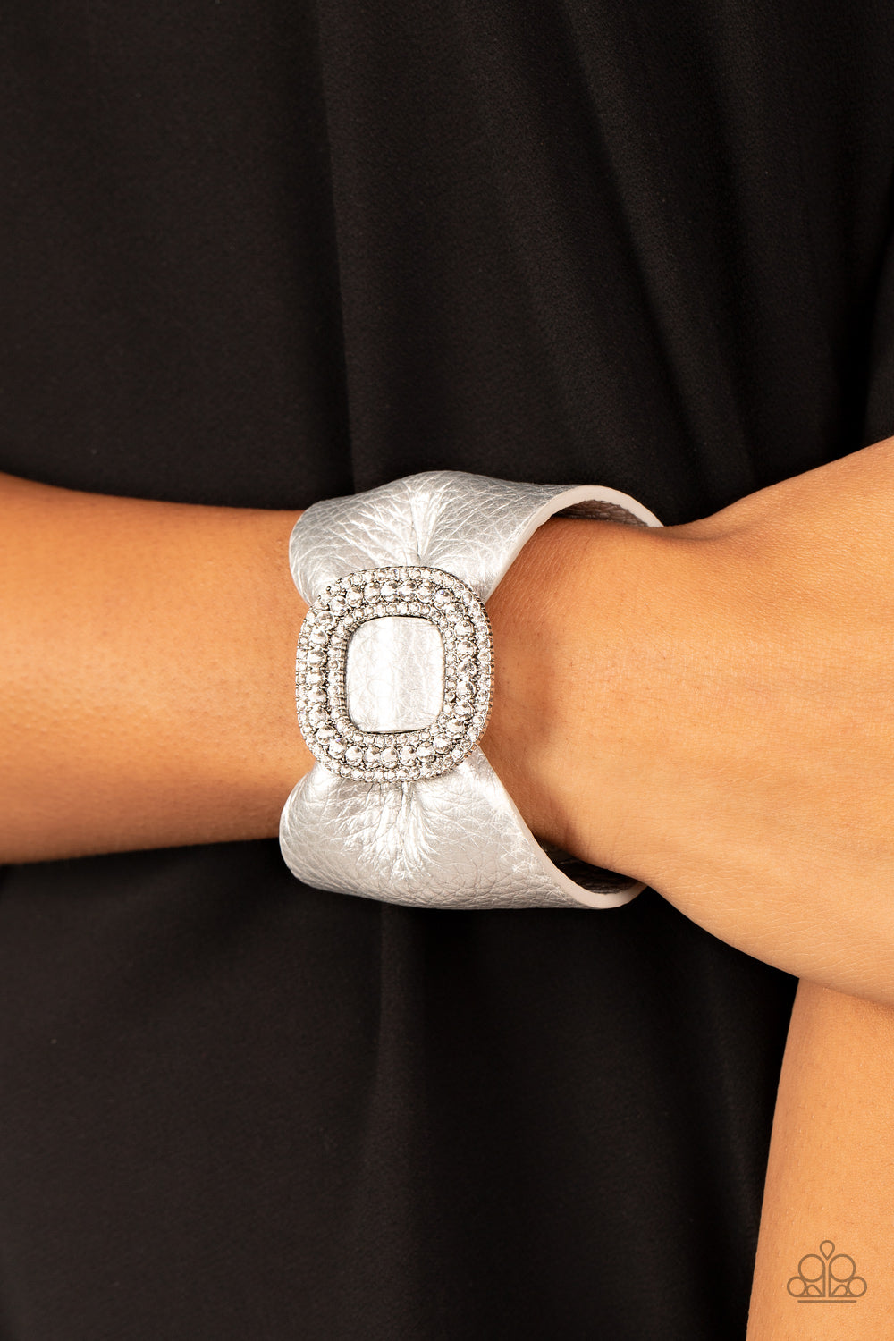 Paparazzi Lights, SELFIE, Action - Silver Bracelets a silver finish, a thick pleather band delicately knots around the wrist. Stacked with brilliant white rhinestones, a dramatic silver buckle sparkles at the center of the wrist for a dramatic finish. Features an adjustable snap closure.  Sold as one individual bracelet.