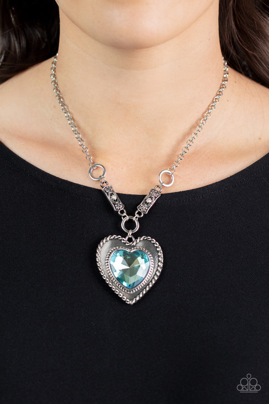 Paparazzi Heart Full of Fabulous - Blue Heart Necklaces bordered in spun silver ribbons, an oversized blue heart gem is pressed into a silver heart frame below the collar. The flirtatious pendant attaches to silver rings and decorative silver frames dotted in white rhinestones, resulting in a dash of vintage inspired romance. Features an adjustable clasp closure.  Sold as one individual necklace. Includes one pair of matching earrings.