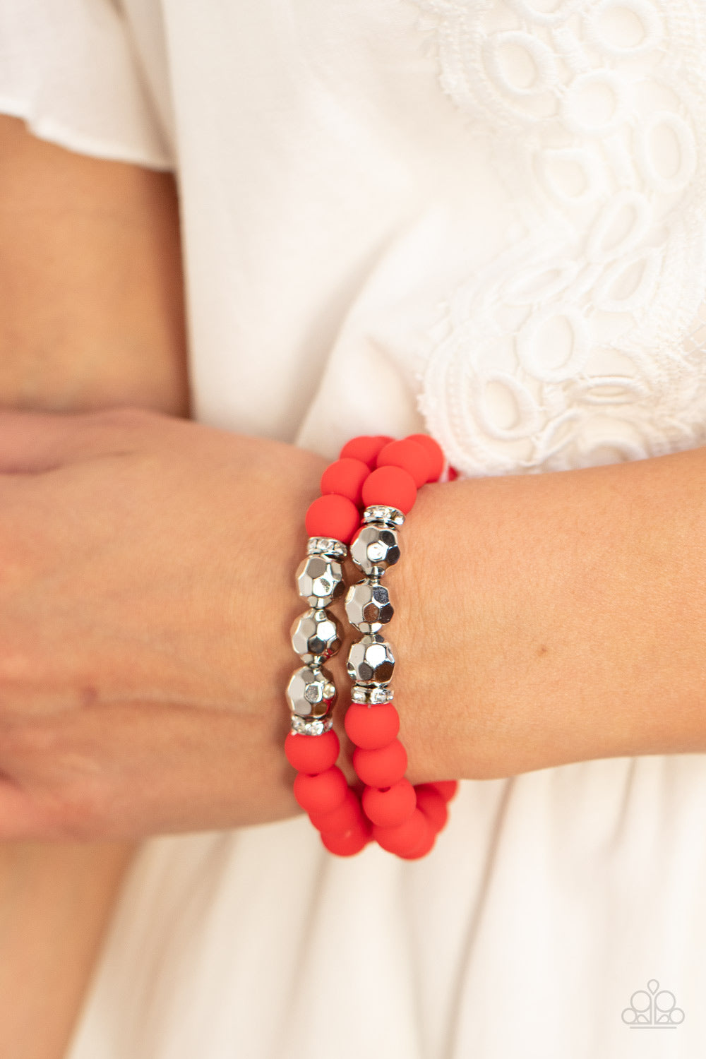 Threaded along invisible wires, matte-finished Poinciana beads give way to center sections of white rhinestone encrusted rings and faceted silver beads. The vivacious display layers below the collar, creating a summery splash of color. Sold as one individual necklace. Includes one pair of matching earrings. he wrist. White rhinestone encrusted rings flank a trio of faceted silver beads along a stretchy row of matte-finished Poinciana beads, creating a summery splash of color around the wrist.