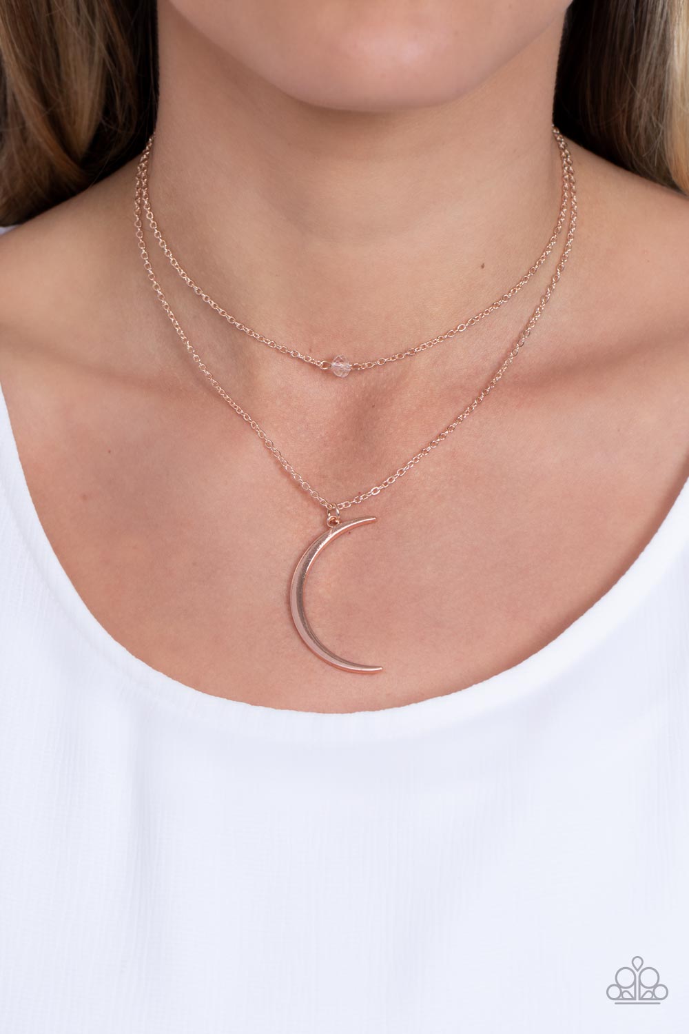 Rose Gold Necklaces two dainty rose gold chains delicately layer below the collar. A white crystal-like bead sparkles at the center of the uppermost chain while a rose gold half moon pendant swings from the bottom of the display for a mystical finish. Features an adjustable clasp closure.  Sold as one individual necklace. Includes one pair of matching earrings.