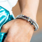 Chiseled pieces of hematite, oil spill stones, and silver beads of various sizes are threaded along a long wire to create an infinity wrap bracelet. Hanging from the end of the design, a silver charm with a smoky star and silver studs completes the shimmering prismatic design around the wrist. Coil design allows for an adjustable fit. Due to its prismatic palette, color may vary.  Sold as one individual bracelet.