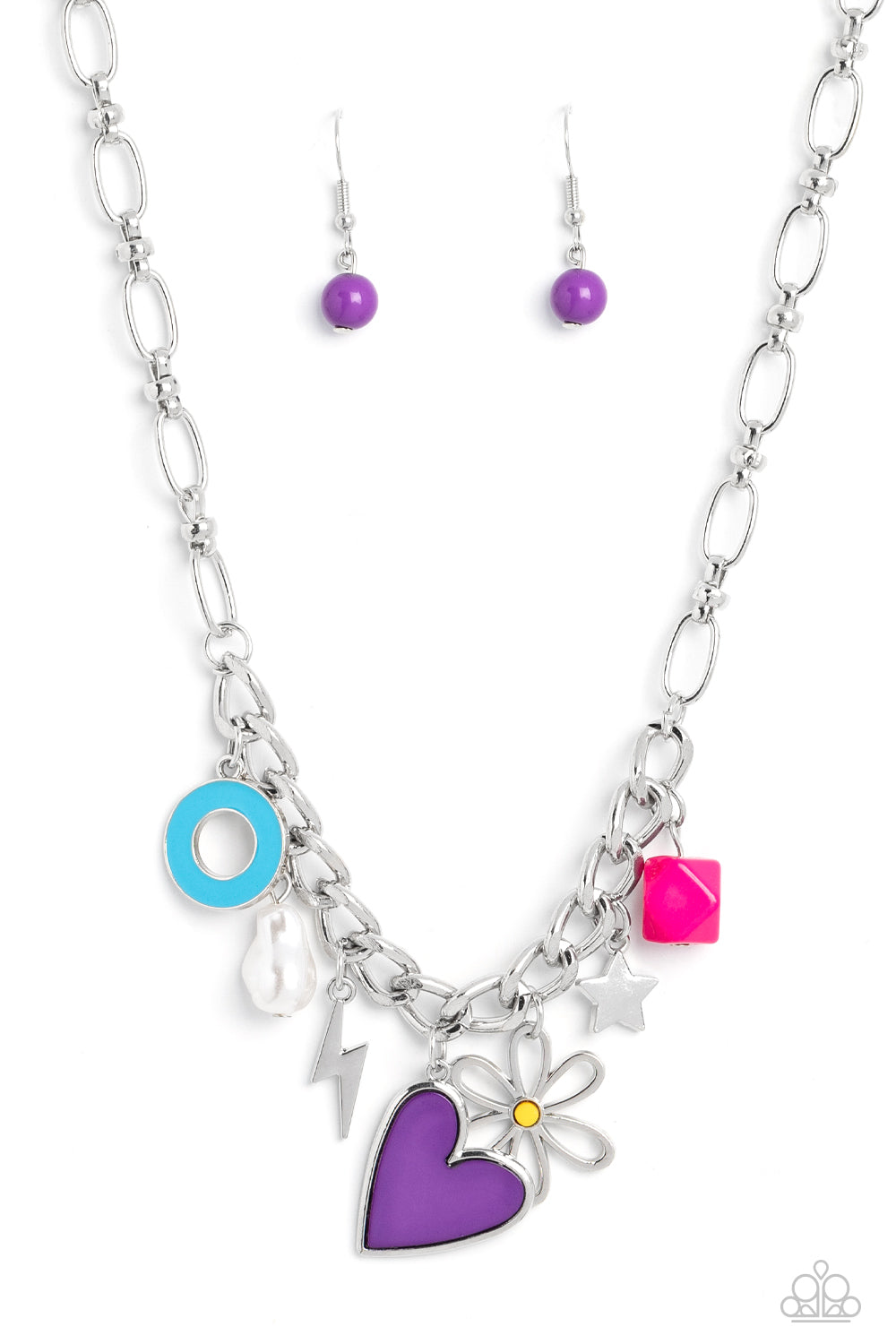 Elongated silver chain links, separated by tiny silver beads, lead down the neckline to a section of thick, flat, silver curb chain. A collection of whimsical charms gather along the thicker chain, including a lightning bolt, a star, a blue ring, a silhouette of a flower, a vibrant pink bead, a purple heart, and a polished white baroque pearl. 