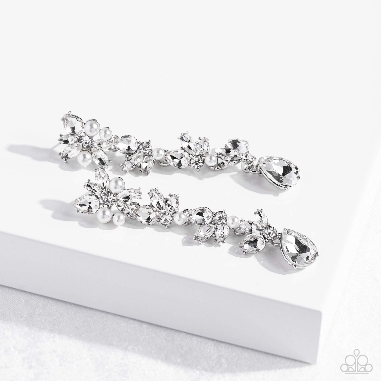 Paparazzi Accessories - LIGHT at the Opera - White 2023 EMP Earrings radiant clusters of white reflective teardrop, marquise-cut and round gems combine with classic white pearls to create an explosion of glitz that extends down the ear. Hanging from the bottom of the light-reflecting earring, a white, reflective teardrop gem swings for some eye-catching shimmer against a backdrop of high-sheen silver. Earring attaches to a standard post fitting.
