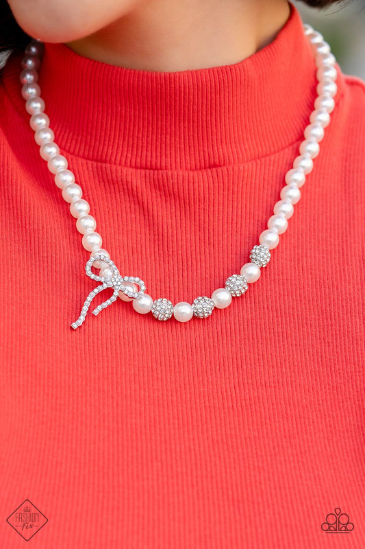 strand of classic white pearls coalesces down the neckline in a feminine display. Airy silver spheres, adorned in sparkling white rhinestones, are effortlessly sprinkled among the sea of pearls on one side, infusing the design with capricious shimmer. Then in the perfect finishing touch, a ribbon of silver, adorned in tiny white pearls and sparkling white rhinestones, loops into a bow at the bottom of the design. Features an adjustable clasp closure.