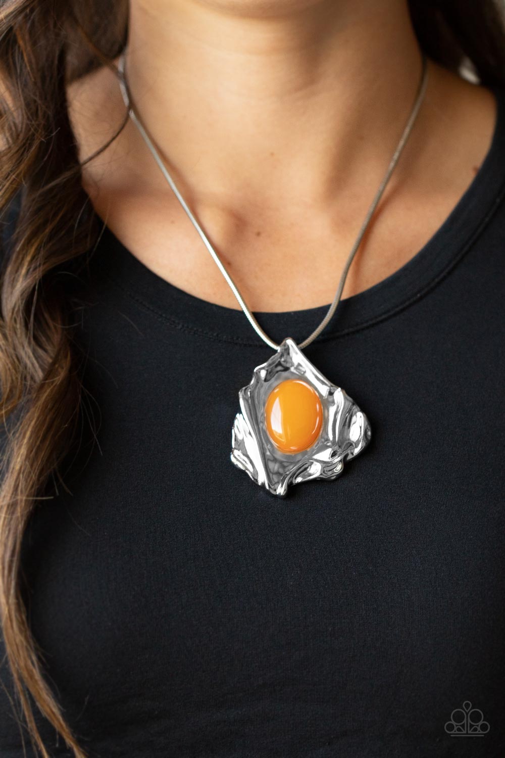 Amazon Amulet - Orange Oval Bead Necklaces a glassy orange oval bead is pressed into the center of an abstract silver frame below the collar, creating a colorful artisan inspired pendant at the bottom of a rounded silver snake chain. Features an adjustable clasp closure.  Sold as one individual necklace. Includes one pair of matching earrings.  Paparazzi Jewelry is lead and nickel free so it's perfect for sensitive skin too!
