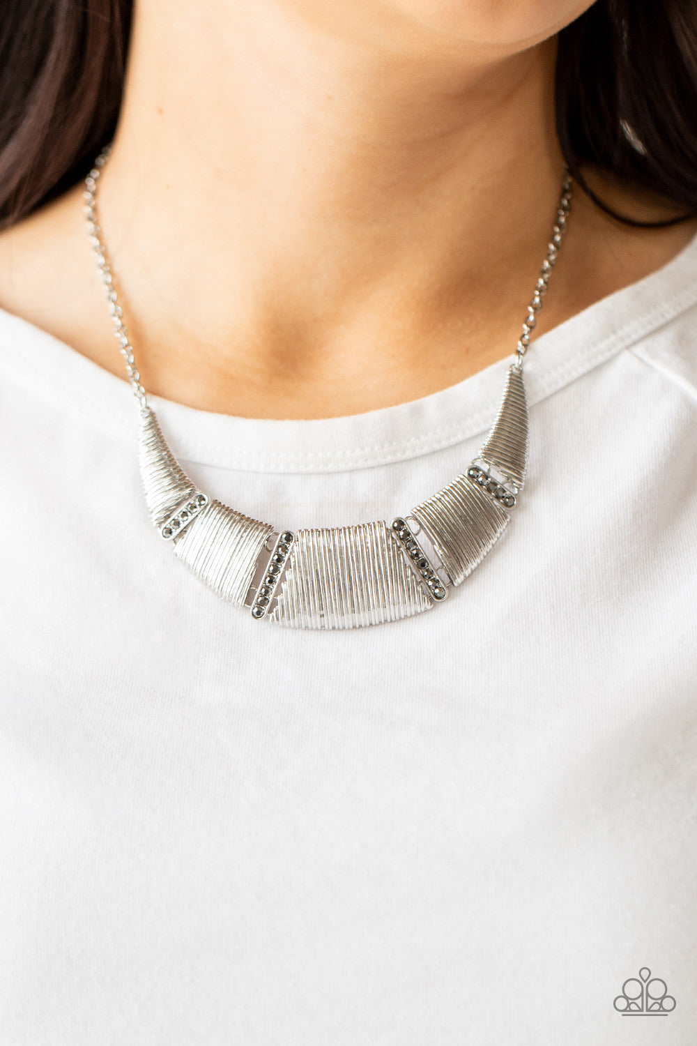 Embossed in linear textures, trapezoidal and triangular silver plates delicately link with dainty hematite rhinestone encrusted frames, creating a dramatic half moon below the collar. Features an adjustable clasp closure.